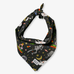A black bandana-style dog collar with a knotted top, featuring a colorful Halloween-themed print with white ghosts, a skeleton, stars, candy corn, a spiderweb, and a moon. A small white fabric label near the bottom reads 'POLICE'.