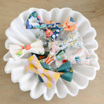Set of colorful fabric bows on a white ceramic plate against a wooden background