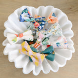 Set of colorful fabric bows on a white ceramic plate against a wooden background